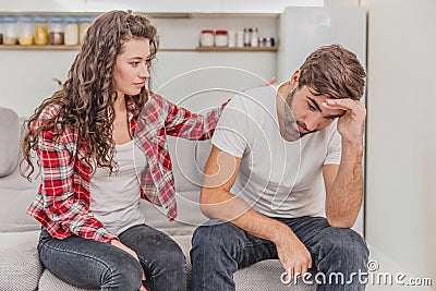 Couple argue. The wife shouted to her desperate husband, sitting on the couch in the living room at home. A man does not Stock Photo