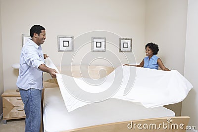 Couple Arranging Bedsheet Stock Photo