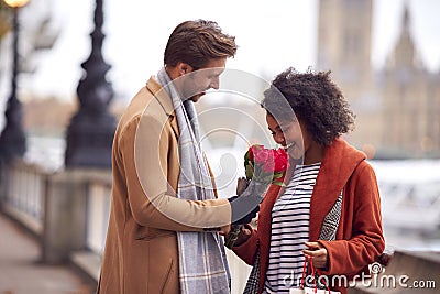 Couple In Autumn Or Fall Meeting On Date In City With Man Giving Woman Bouquet Of Flowers Stock Photo