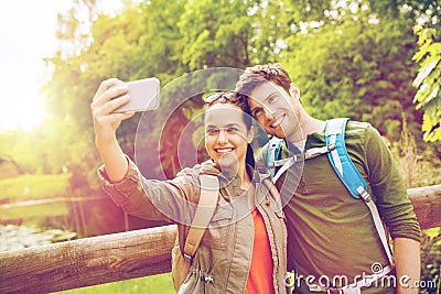 Couple with backpacks taking selfie by smartphone Stock Photo