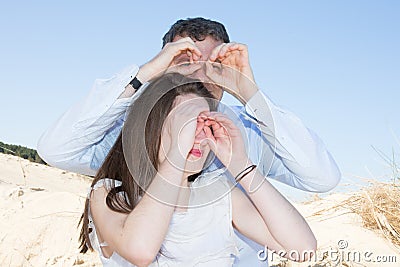 Couple on the beach play binoculars Stock Photo