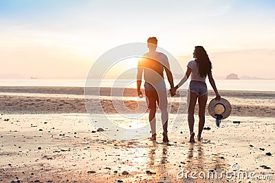 Couple On Beach At Sunset Summer Vacation, Beautiful Young People In Love Walking, Man Woman Holding Hands Stock Photo