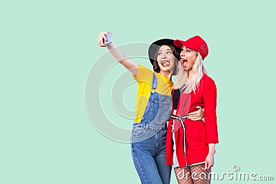 Couple of beautiful stilysh hipster best friends in fashionable clothes hugging with love, posing for camera and making selfie or Stock Photo