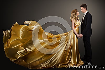 Couple, Beautiful Woman in Golden Silk Dress and Elegant Man, Fluttering Gown Stock Photo