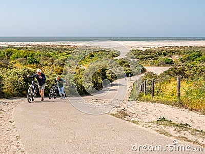 Couple with bicycles on steep hill of Duinhoevepad in dunes near Renesse on Schouwen-Duiveland, Zeeland, Netherlands Editorial Stock Photo