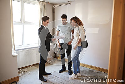 Couple Buying House For The First Time Looking At Survey With Realtor Stock Photo