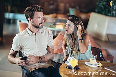 Couple in a cafe spends leisure time together, she is angry because he is busy on the phone Stock Photo