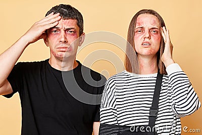 Couple after car accident. Robbery beating. man and woman with bruise isolated over beige background family suffering terrible Stock Photo