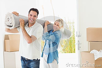 Couple carrying rolled rug after moving in a house Stock Photo