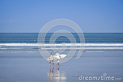 Couple carrying surboards kuta beach bali Editorial Stock Photo