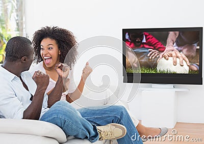 Couple cheering while watching rugby match on television Stock Photo