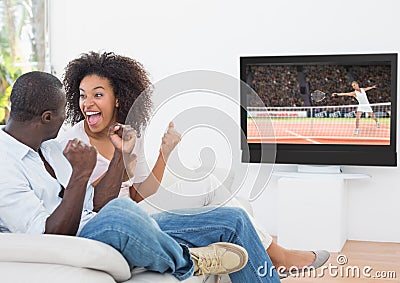 Couple cheering while watching tennis match on television Stock Photo