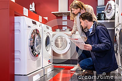 Couple Choosing Washing Machine At Hypermarket Stock Photo