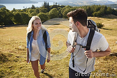 Couple Climbing Hill On Hike Through Countryside In Lake District UK Together Stock Photo