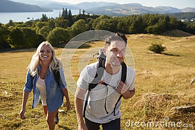 Couple Climbing Hill On Hike Through Countryside In Lake District UK Together Stock Photo