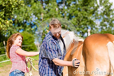 Couple combing horse on pony farm Stock Photo