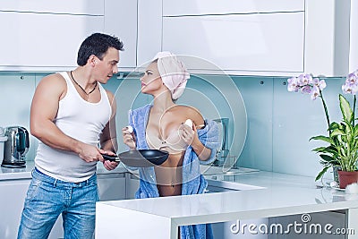 Couple cooking in kitchen. Sexy young family or lovers in kitchen cooking breakfast. Stock Photo