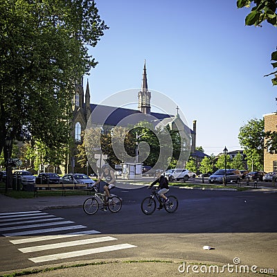 A couple cycling in Charlottetown in the morning with St.Dunstan`s Basilica Cathedra in the background Editorial Stock Photo