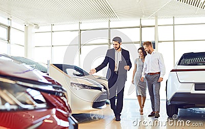 Couple and the dealer selling cars look the car in the showroom. Stock Photo