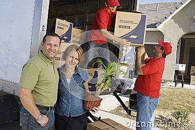 Couple With Delivery Men Unloading Moving Boxes From Truck Stock Photo