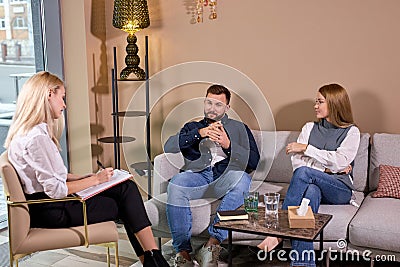 couple talking about problems to marriage counselor before breaking up, consulting family relationships expert,in office Stock Photo