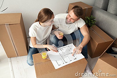 Couple discussing house plan sitting on floor with moving boxes Stock Photo