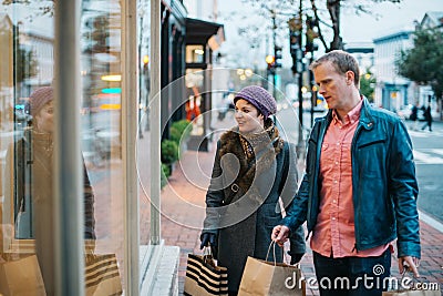 Couple dressed in warm clothing window shopping outdoors Stock Photo