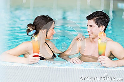 Couple drinking a cocktail by the swimming pool Stock Photo