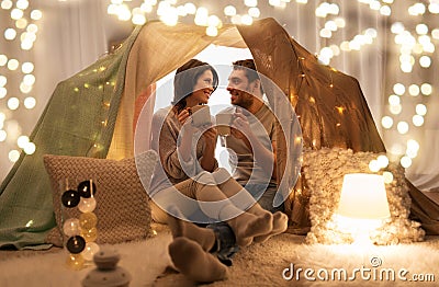 Couple drinking coffee or tea in kids tent at home Stock Photo