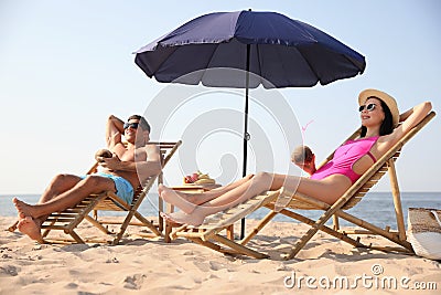 Couple with drinks resting on beach at resort Stock Photo