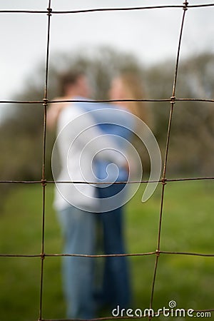 Couple embracing behind a fence Stock Photo