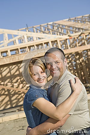 Couple Embracing In Front Of Incomplete House Stock Photo