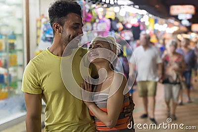 Couple Embracing On Street Market, Mix Race Man And Woman Happy Smiling Looking At Each Other Stock Photo