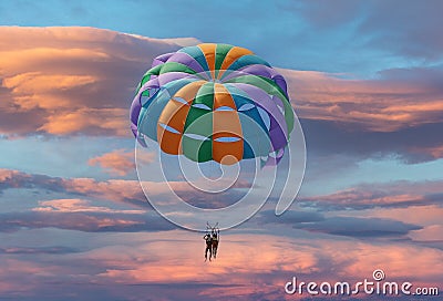 Couple enjoy parasailing flight during sunset Stock Photo