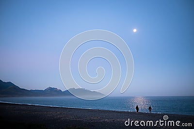 A couple enjoying the moon lit landscape. The environment is quiet and peaceful. This was taken in Kaikoura, New Zealand. Couple Stock Photo