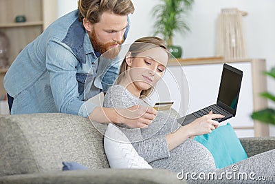 couple enjoying online shopping sitting on sofa at home Stock Photo