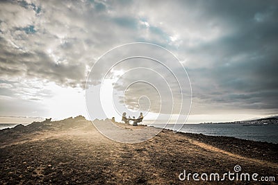 Couple enjoying the outdoor freedom and leisure activity sitting in front of the ocean. travel and alternative vacation concept Stock Photo