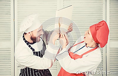 Couple fight for book recipes. Improve cooking skill. Book recipes. Helpful culinary book. Woman chef and man cooking Stock Photo