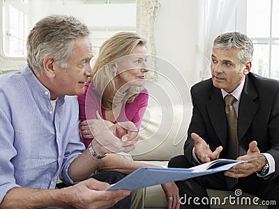 Couple With Financial Advisor At Sofa Stock Photo