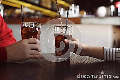 Couple with glasses of cola at table indoors, closeup. Stock Photo