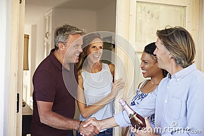 Couple greeting their guests at the door of their home Stock Photo