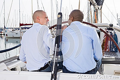 A couple of guys in blue shirts chatting on private yacht in the port Stock Photo