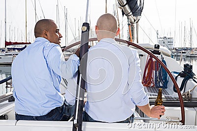 Couple of guys in blue shirts chatting on private yacht in the port Stock Photo