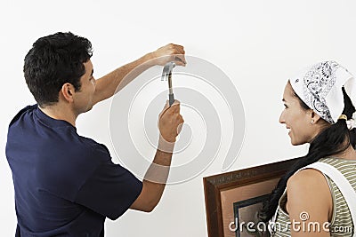 Couple Hammering Nail Into Wall Stock Photo