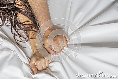 Couple hands pulling white sheets in ecstasy, orgasm. Concept of passion. Oorgasm. Erotic moments. Intimate concept. Sex Stock Photo