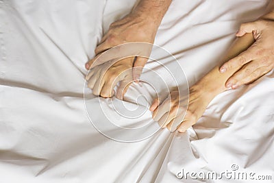 Couple hands pulling white sheets in ecstasy, orgasm. Concept of passion. Oorgasm. Erotic moments. Intimate concept. Sex Stock Photo