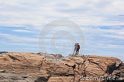 Couple of happy hispanics people standing backs on top of cliff and overlooking stunning view to Atlantic ocean Stock Photo