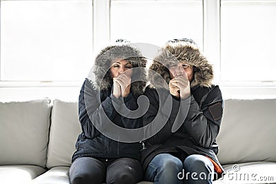 Couple have cold on the sofa at home with winter coat Stock Photo