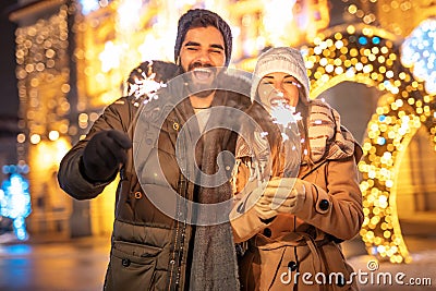 Couple having fun celebrating New Year outdoors waving with sparklers Stock Photo