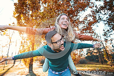 Couple having fun man giving piggyback to woman Stock Photo